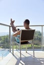 Man using a smartphone and sunbathing in a chair