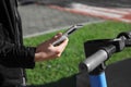 Man using smartphone to pay and unblock rental electric scooter outdoors, closeup