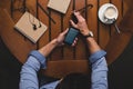 overhead view of man using smartphone with twitter website while sitting at table with coffee