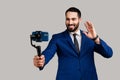 Man using stedicam and phone for livestream, waving hand to followers, content for business vlog.