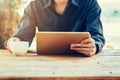 Man using tablet on table in coffee shop with vintage toned filter. Royalty Free Stock Photo