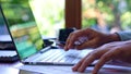 Man using touch screen laptop at desk in front of window, close up. Royalty Free Stock Photo