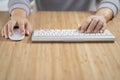 Man using white computer keyboard and mouse on the wooden desk Royalty Free Stock Photo