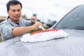 Man using white mop with soap to washing the car at outdoor. Car cleaning and maintenance concept Royalty Free Stock Photo