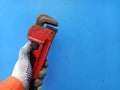 Man using work glove holding rusty red pipe wrench or monkey wrench Royalty Free Stock Photo