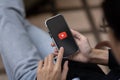 A man using Youtube application on his iPhone while sitting outdoors. close-up image