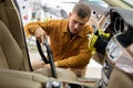 Man vacuuming driver seat in car using portable blower machine