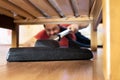 Man vacuuming a floor under a bed at home Royalty Free Stock Photo