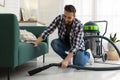 Man vacuuming floor under sofa in living room Royalty Free Stock Photo