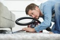 man vacuuming floor under sofa Royalty Free Stock Photo
