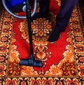 A man is vacuuming an old carpet. Royalty Free Stock Photo