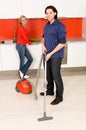 Man vacuuming, woman in background