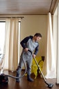 Man vacuuming wooden floor at home Royalty Free Stock Photo