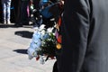 A man in a jacket with orders and medals on his chest holding a bouquet of white flowers