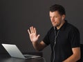 Man in Video conferencing call via laptop and greeting colleagues.