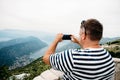 A man is on the view point near Kotor bay and take a picture of the view on his smartphone. Travel concept