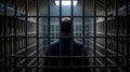 Man viewed from behind in a dark prison cell looking towards a light source Royalty Free Stock Photo
