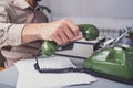 Man in vintage office uses green rotary telephone
