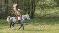 A man in vintage poland armor with wings. A legion of volatile hussars riding a horse to attack in battle