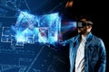 A man in virtual reality glasses designs a building a hologram of a house. Construction, architecture concept. Mixed environment