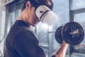 Man in virtual reality headset exercising with dumbbell in gym Royalty Free Stock Photo