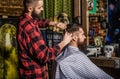 Man visiting hairstylist in barbershop. Hairdresser does styling with a comb in barbershop. Bearded man in barber shop Royalty Free Stock Photo