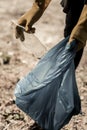 Man volunteering in forest wearing yellow gloves while gathering empty bottles