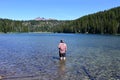 Man wading in Todd Lake, Oregon, with Broken Top in background. Royalty Free Stock Photo