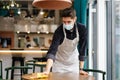Man waiter wearing mask disinfecting table in the cafe