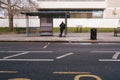 Man waiting for a bus at empty bus stop on rainy day