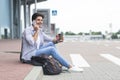 Man waiting outside of airport, drinking coffee and talking on cellphone Royalty Free Stock Photo