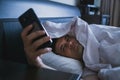 Man wakes up in bed and looks at phone, turns off alarm and looks at time, surf Internet, reads messages Royalty Free Stock Photo