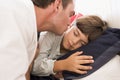 Man waking young boy in bed with kiss Royalty Free Stock Photo