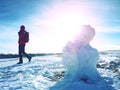 Man walk at icy snowman melting on snowy place