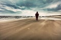 Man walking alone on the beach on windy stormy day Royalty Free Stock Photo
