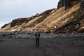 A man walking alone on black sand beach with cliff Royalty Free Stock Photo