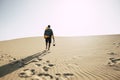 Man walking alone on desert sand dunes - explore and adventure outdoor leisure activity - camera and backpack equipment to enjoy Royalty Free Stock Photo