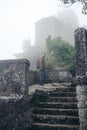 Man walking alone. Fortification on top of the mountain, old castle. Journey. Mystical atmosphere, fog, white haze, mist. Summer