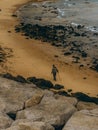 Man walking alone on a rocky beach, gripping a walking stick as he gazes out into the horizon Royalty Free Stock Photo