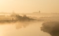 Man walking along banks of river on misty morning