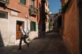 Man is walking along the narrow and bright streets of sunny Venice, Italy