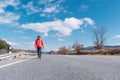 A man walking on the asphalt road under a blue sky with some clouds Royalty Free Stock Photo