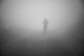 Man walking away on misty road. Man standing alone on rural foggy and misty asphalt road