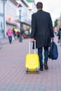 Man walking away pulling a yellow suitcase Royalty Free Stock Photo