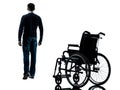 Man walking away from wheelchair silhouette Royalty Free Stock Photo
