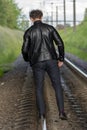 Man walking balancing on railroad tracks. Concept: dangerous walk, carelessness and recklessness, risk to life.