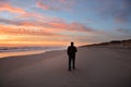 Man walking on beach at beautiful sunrise.