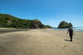 A man is walking on the beach in Piha, New Zealand