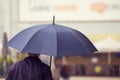 A man walking in the city with a black umbrella on a rainy and windy day Royalty Free Stock Photo