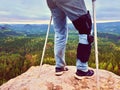 Man Walking With Crutches in nature. Man legs in jeans with adjustable Bandage on pain knee.